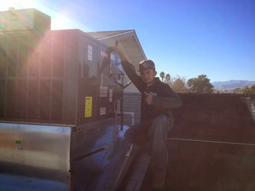 HVAC technician performing AC Tune-Up on a rooftop unit in Orange Beach